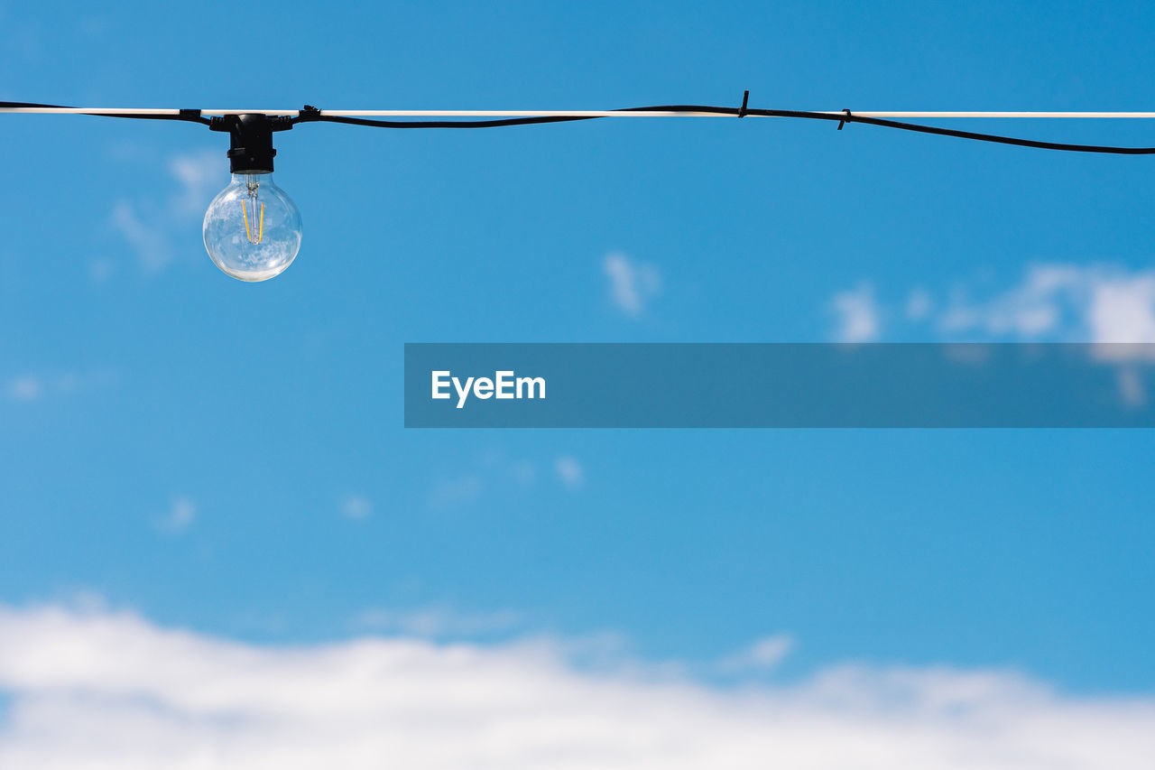 Vintage light bulb with blue sky and white clouds on background. electricity concept. earth hour.