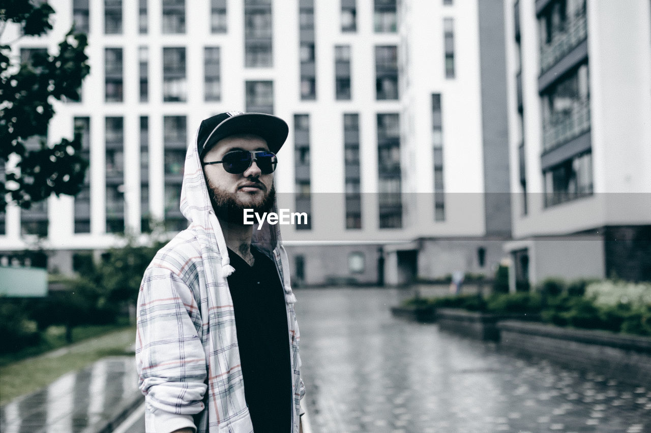 Young man wearing sunglasses while standing against building