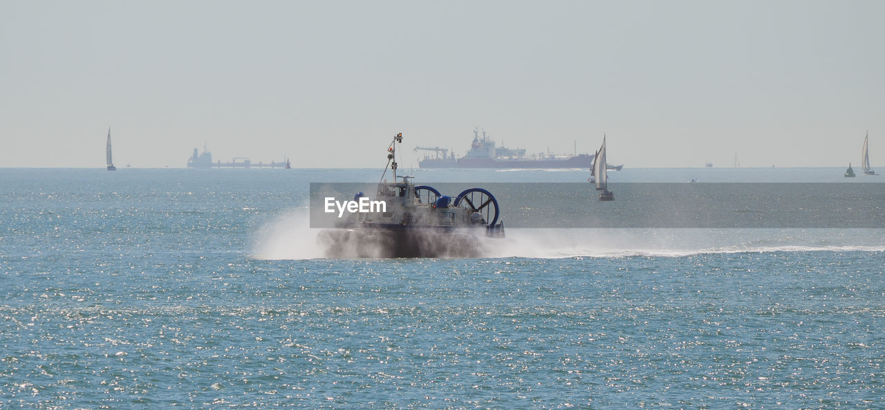 WATER SPLASHING ON SEA AGAINST CLEAR SKY