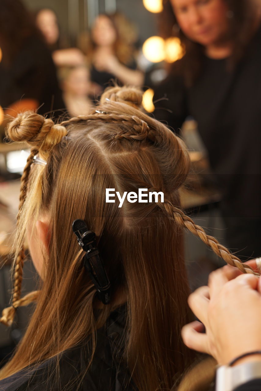 Hairstylist plaiting young woman's hair for a fashion show during nyfw