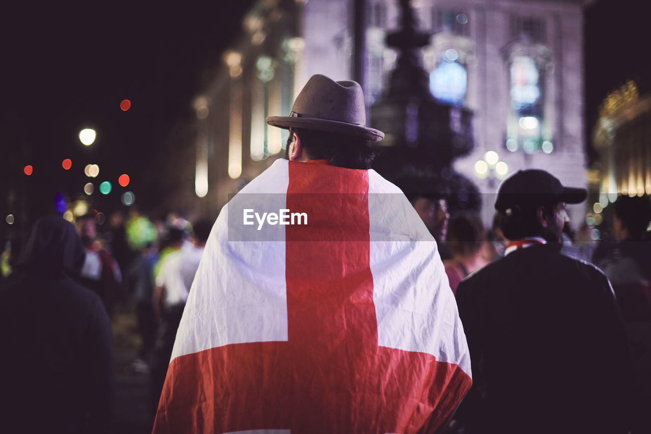 Rear view of person draped in england flag at night