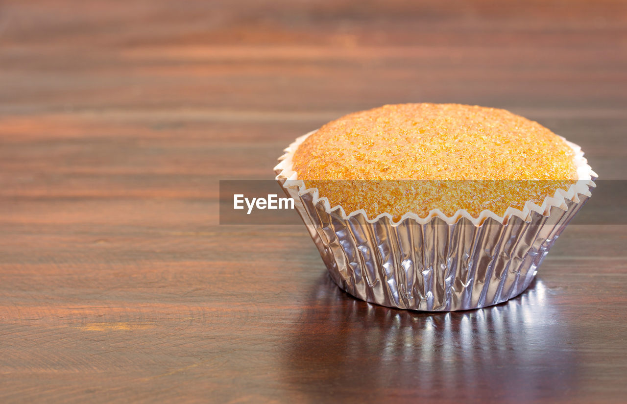 CLOSE-UP OF CUPCAKES ON TABLE AGAINST ORANGE WALL