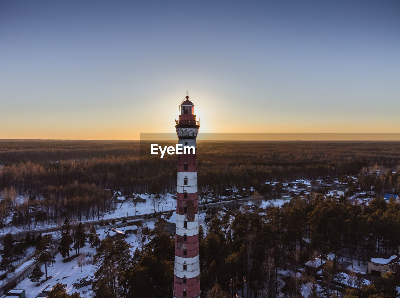 Lighthouse on the shore of the lake, illuminated by the rays of the evening sun. aerial photography
