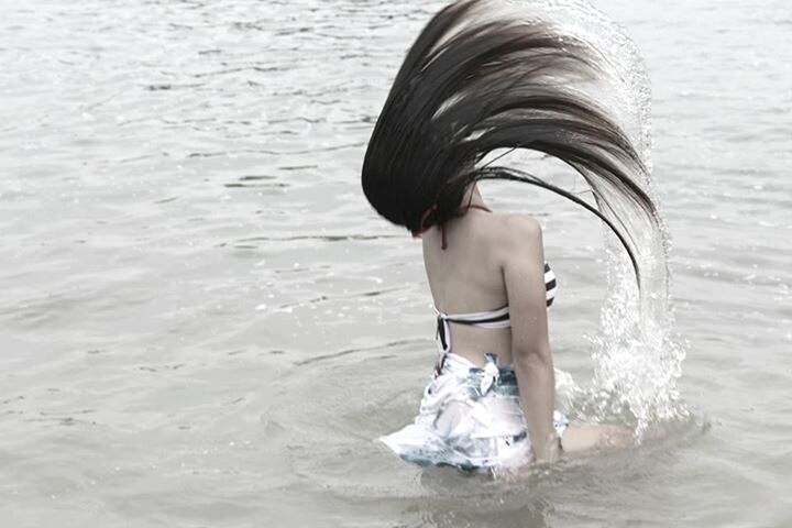 Rear view of young woman flipping hair in water