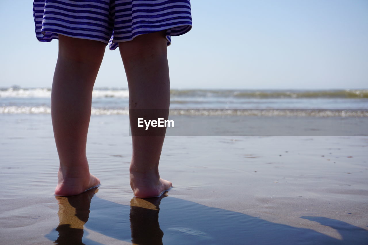 Low section of woman standing at beach