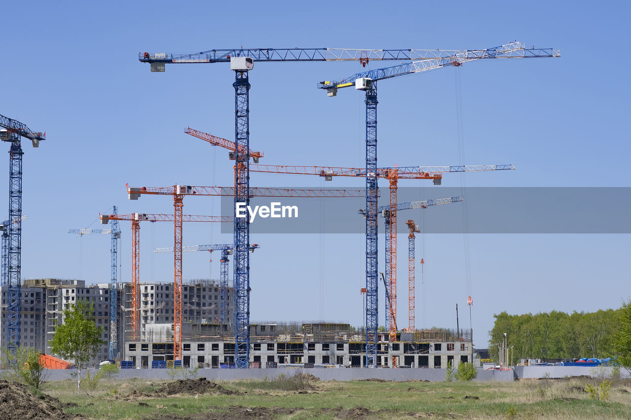 cranes at construction site against sky