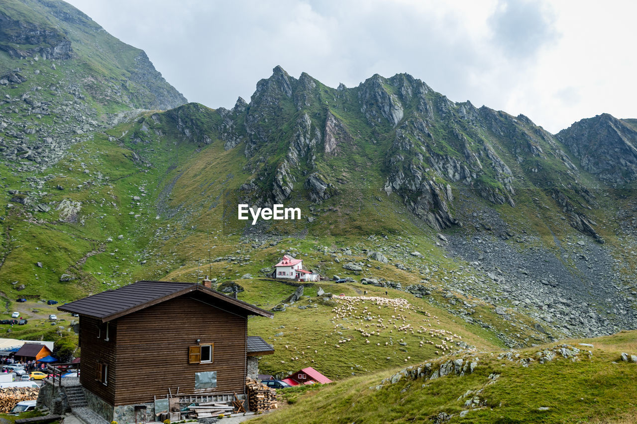 HOUSES BY MOUNTAIN AGAINST SKY