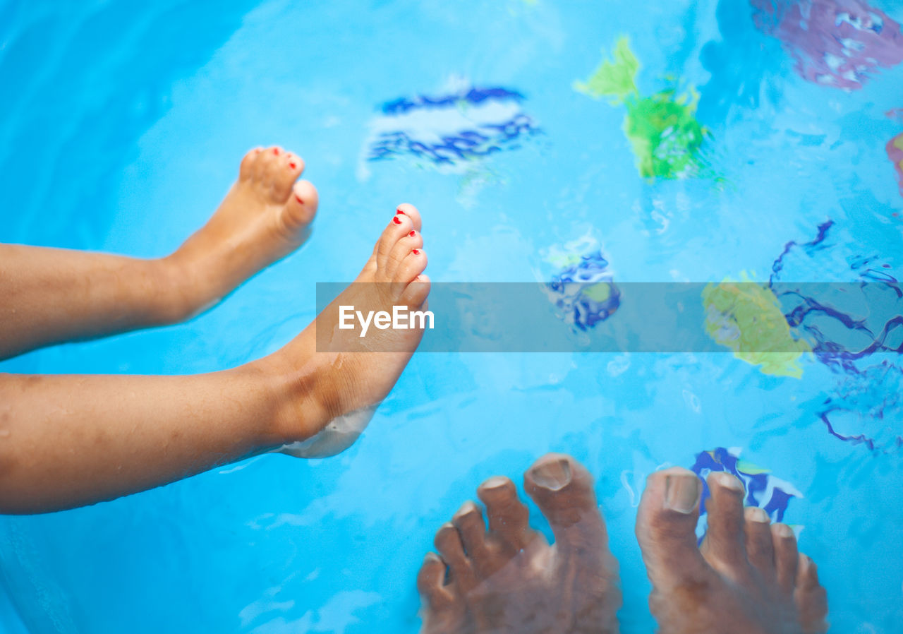 Low section of woman relaxing by swimming pool