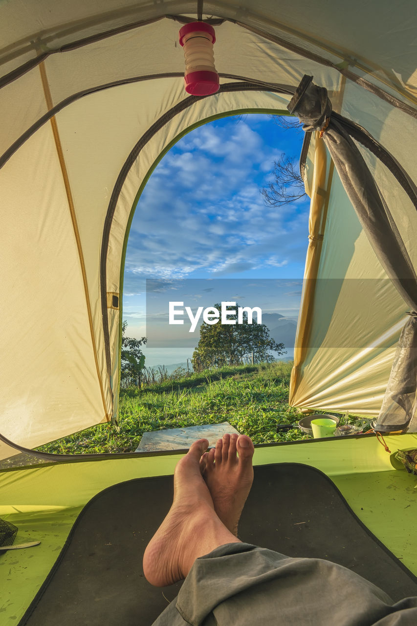 Low section of man relaxing in tent