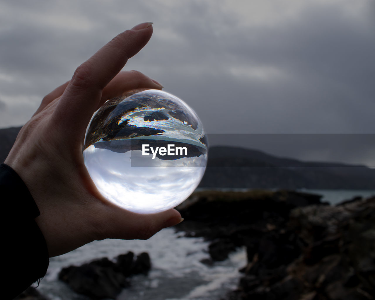 CROPPED IMAGE OF HAND HOLDING GLASS AGAINST SKY