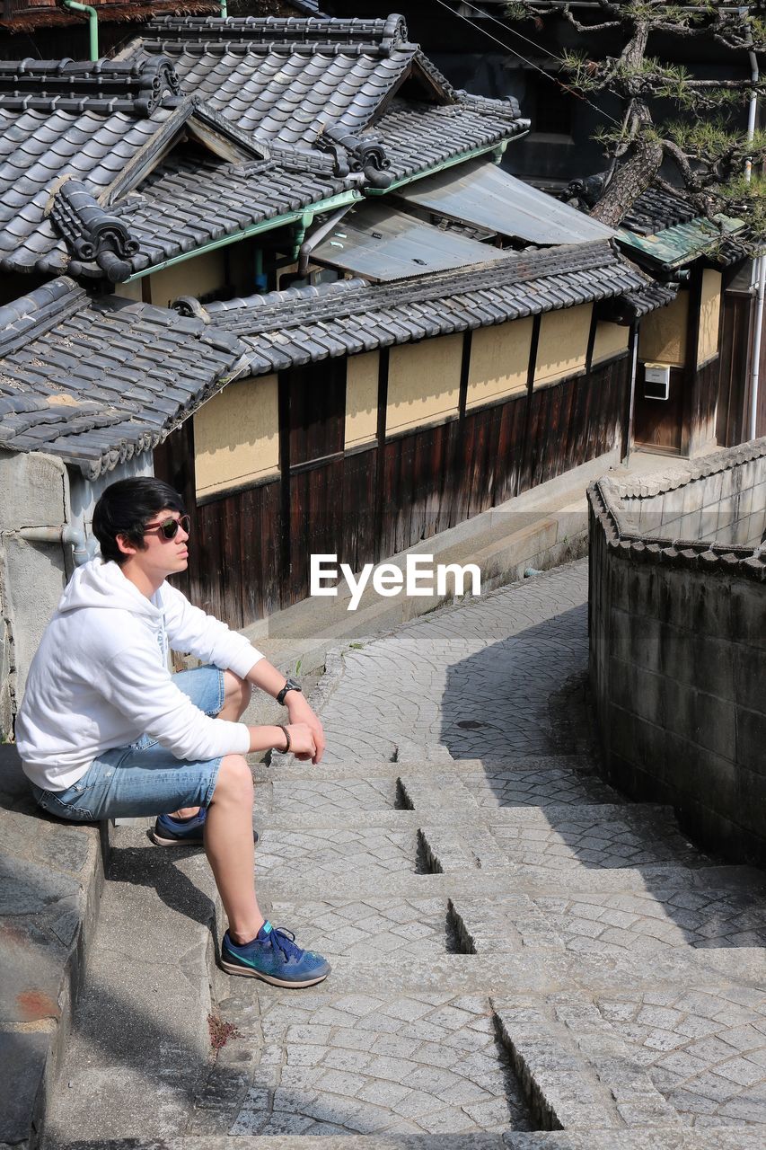 Young man sitting on steps against building