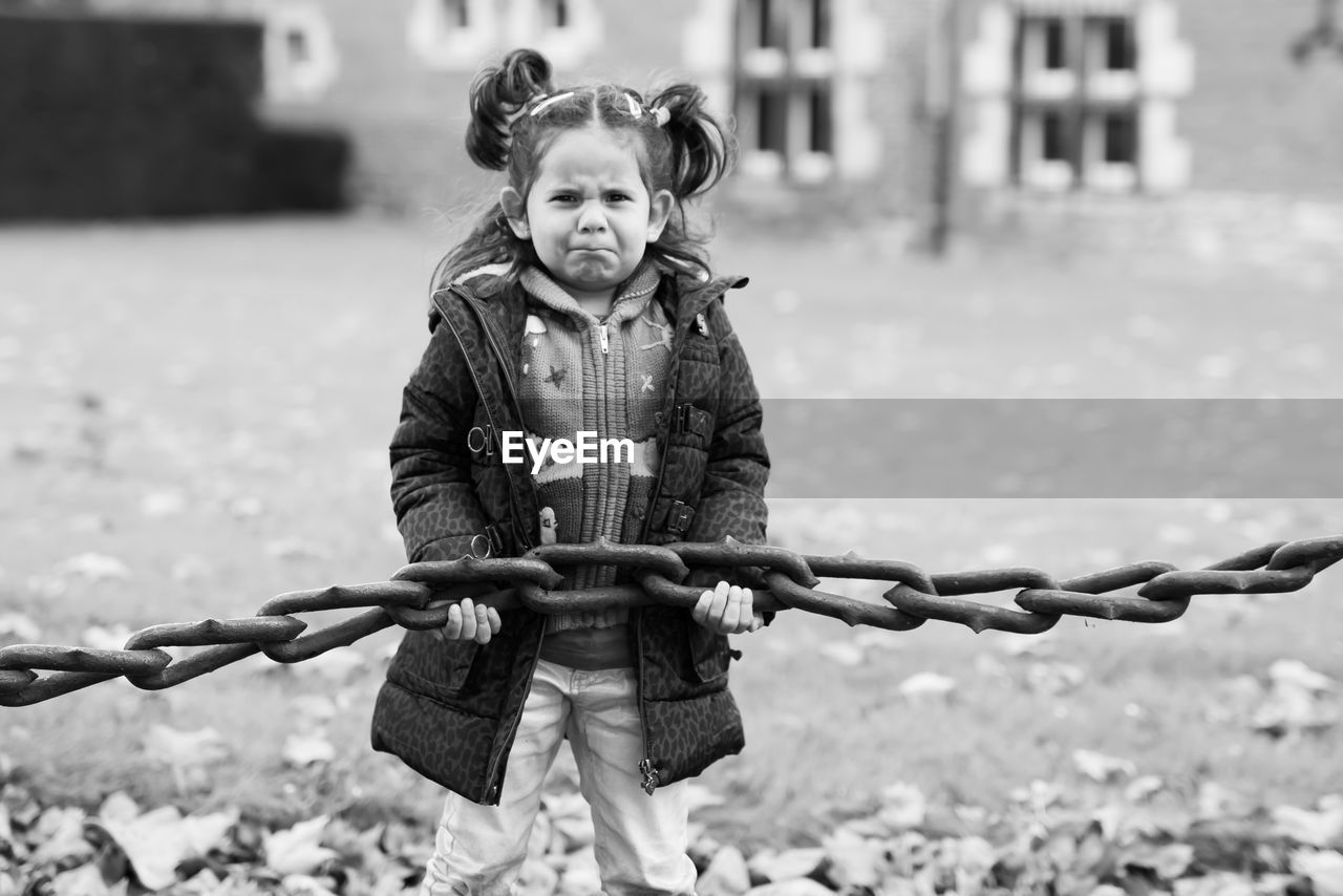 Portrait of cute girl holding chain outdoors