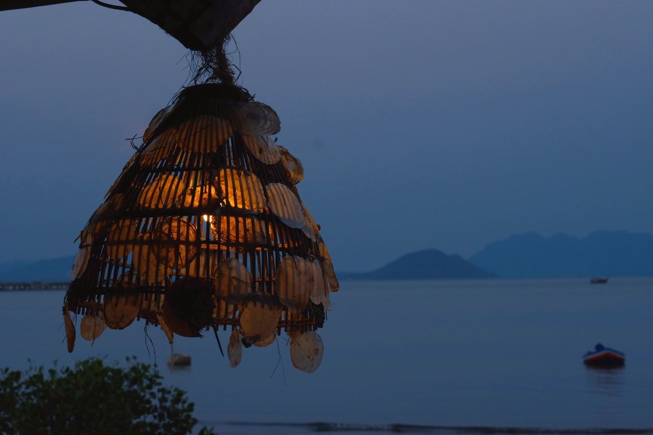 LOW ANGLE VIEW OF UMBRELLAS HANGING AGAINST SKY AT DUSK