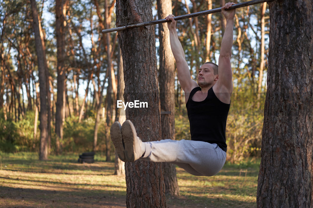 Full length of man exercising at forest