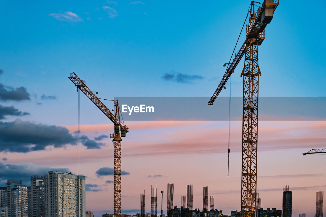 Large construction site with cranes working on a building complex, with sunset sky