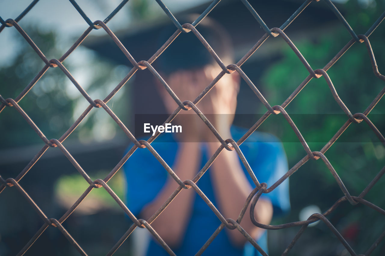 CLOSE-UP OF CHAINLINK FENCE AGAINST BLUE SKY