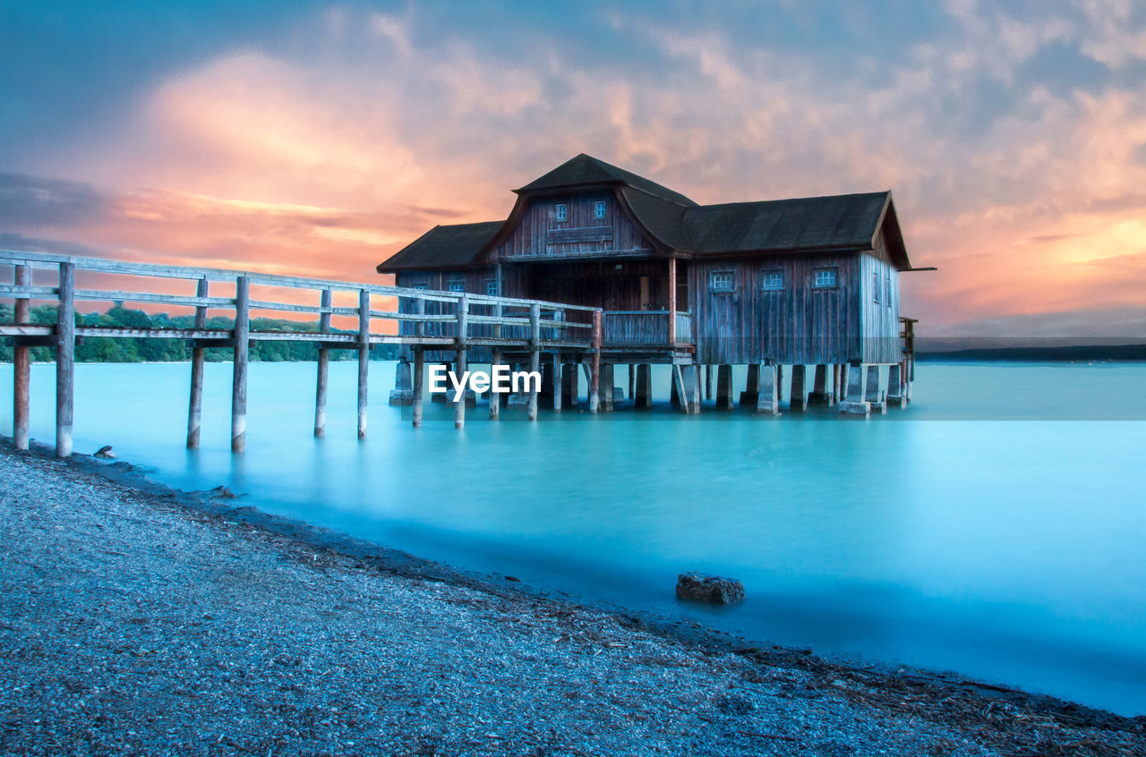 Scenic view of sea and a boathouse against sky during sunset