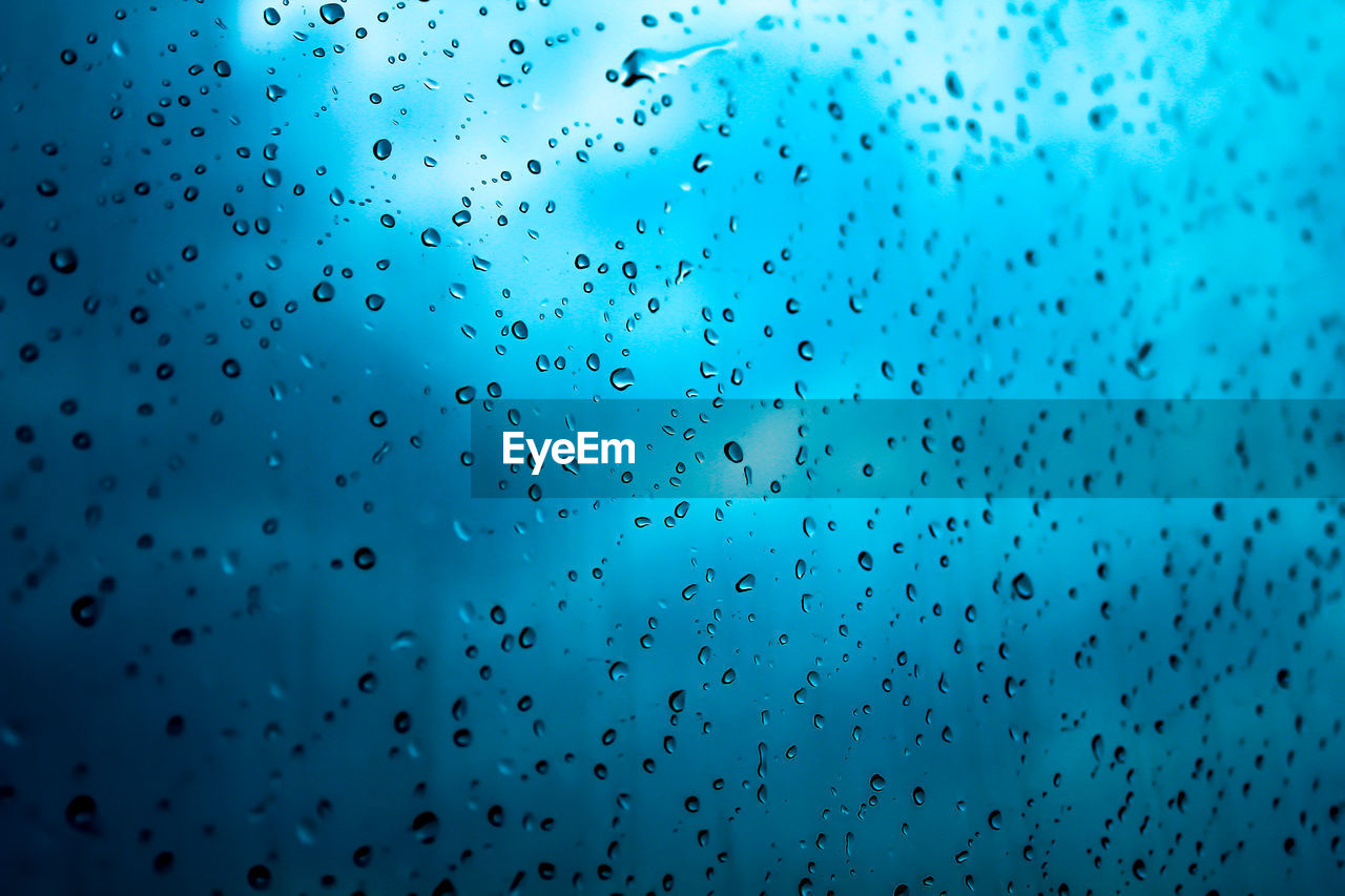 LOW ANGLE VIEW OF RAINDROPS ON GLASS WINDOW