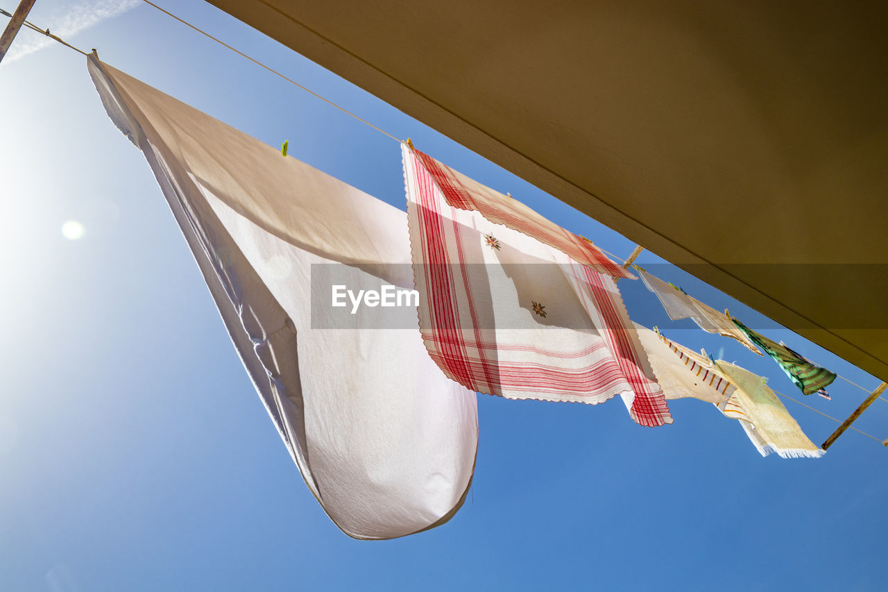 LOW ANGLE VIEW OF FLAG HANGING AGAINST CLEAR SKY