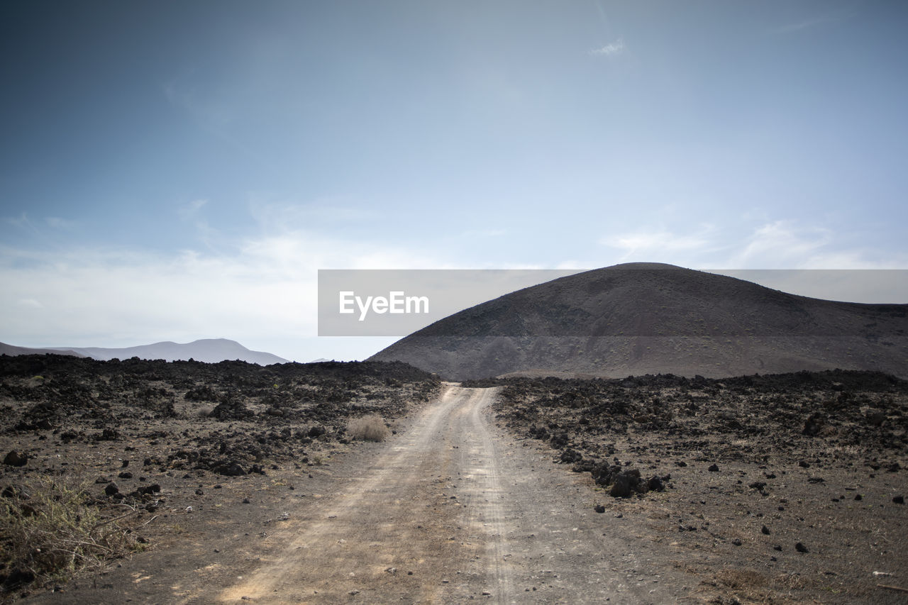 DIRT ROAD ON MOUNTAIN AGAINST SKY