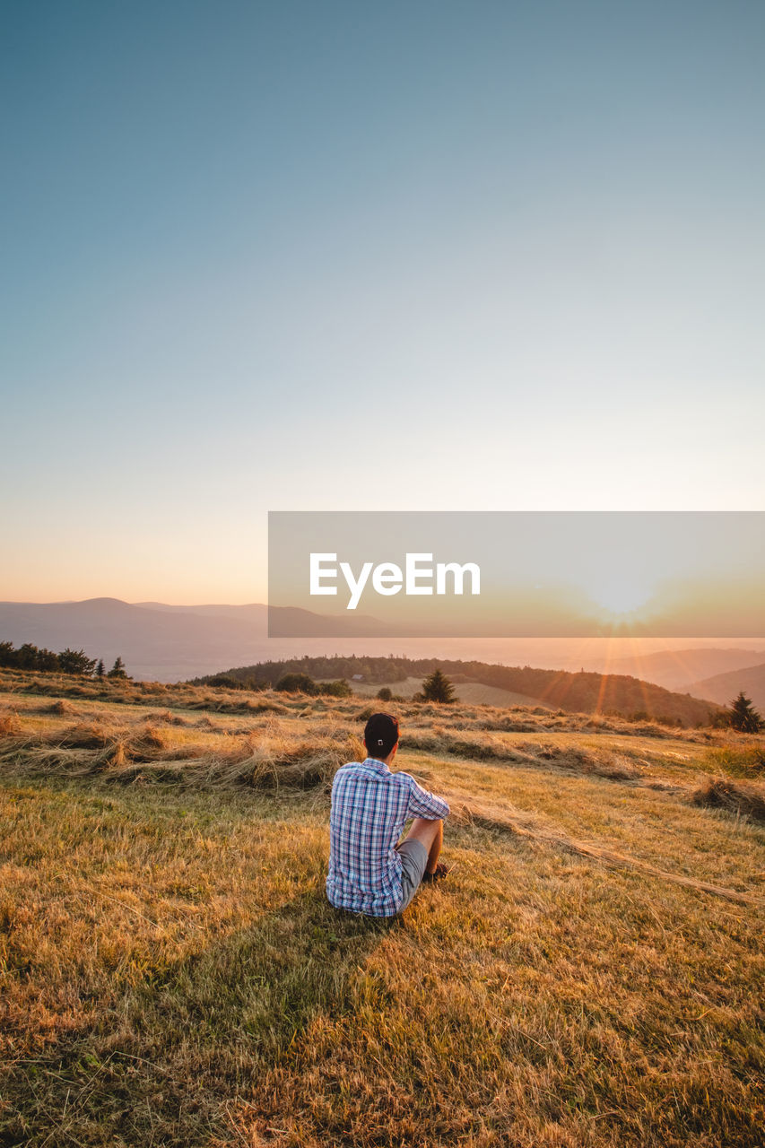 Man in shirt watching sunset. soaking up positive energy and relieving stress