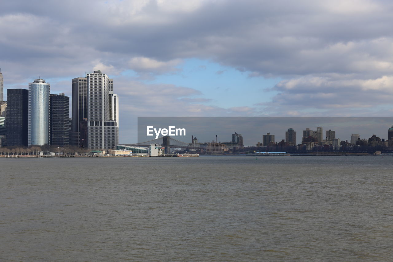 SEA AND BUILDINGS AGAINST SKY IN CITY