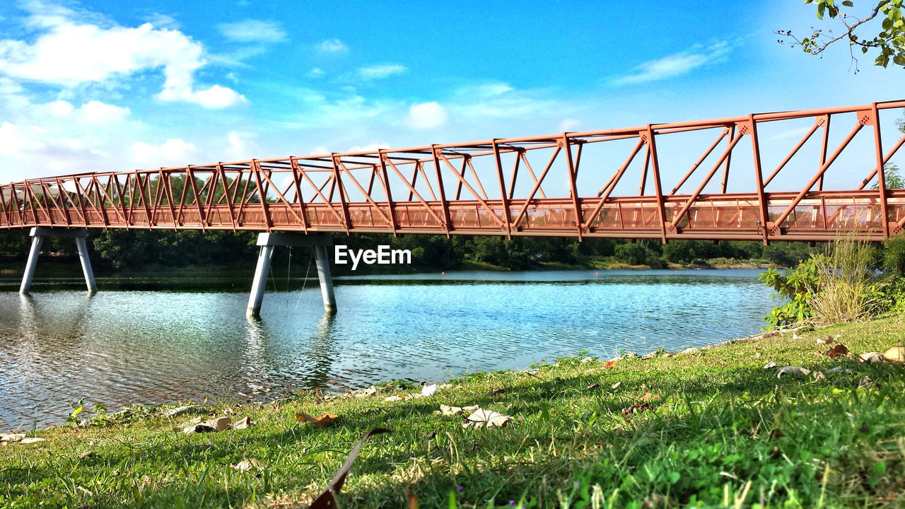 Low angle view of bridge over river against blue sky