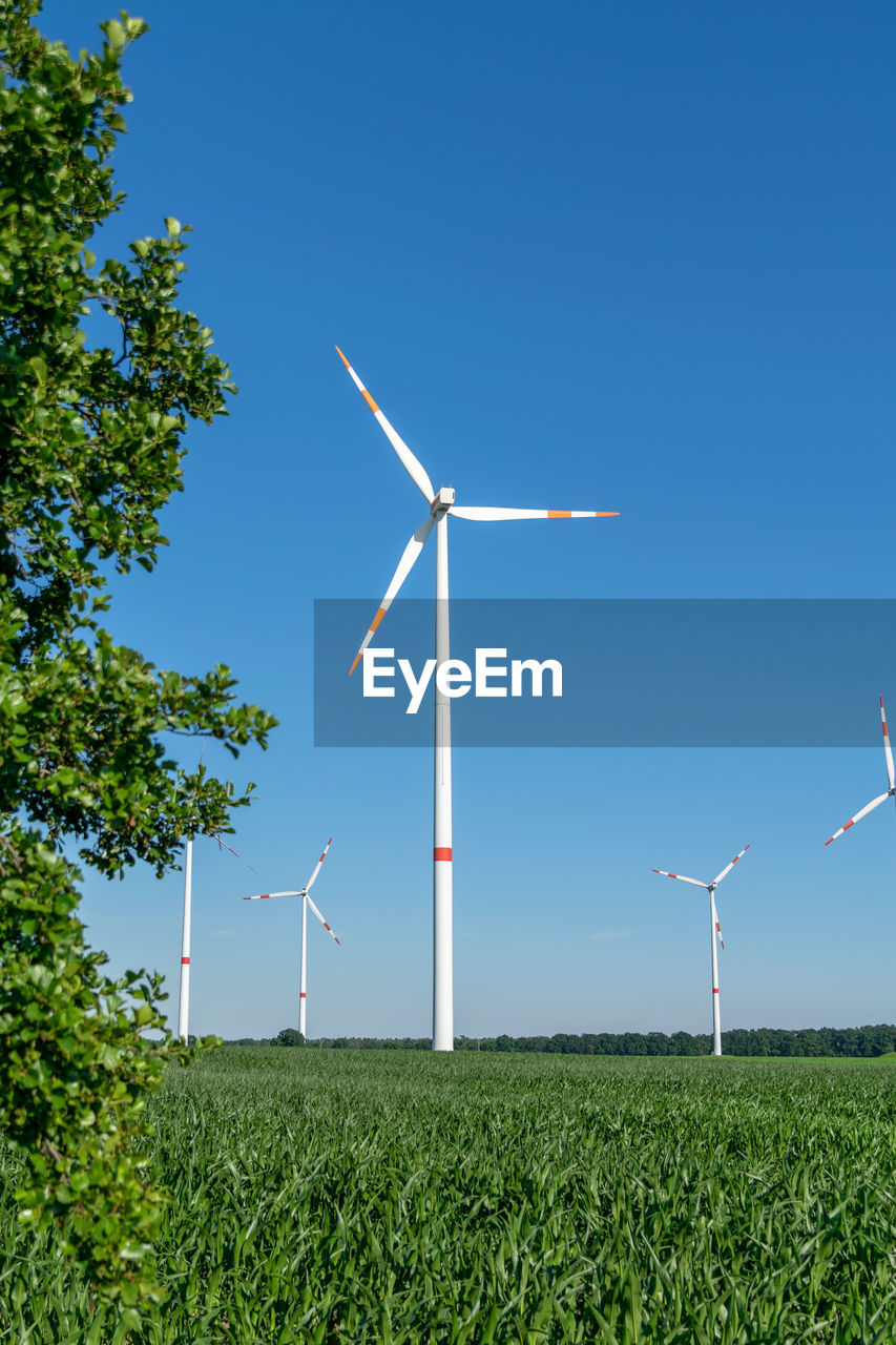 Five wind power turbines, part of a wind farm, on a green field near cottbus, brandenburg, germany.
