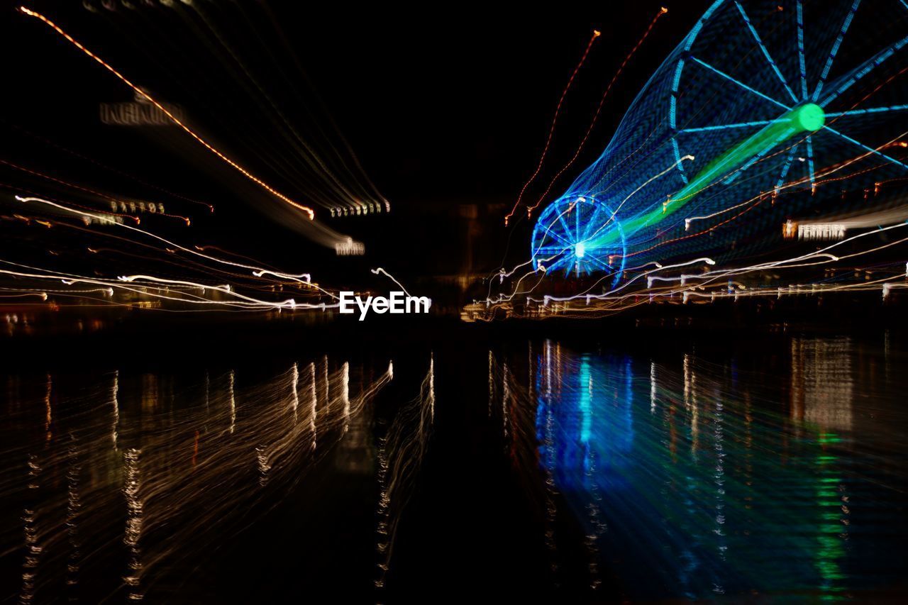ILLUMINATED BRIDGE OVER WATER AT NIGHT