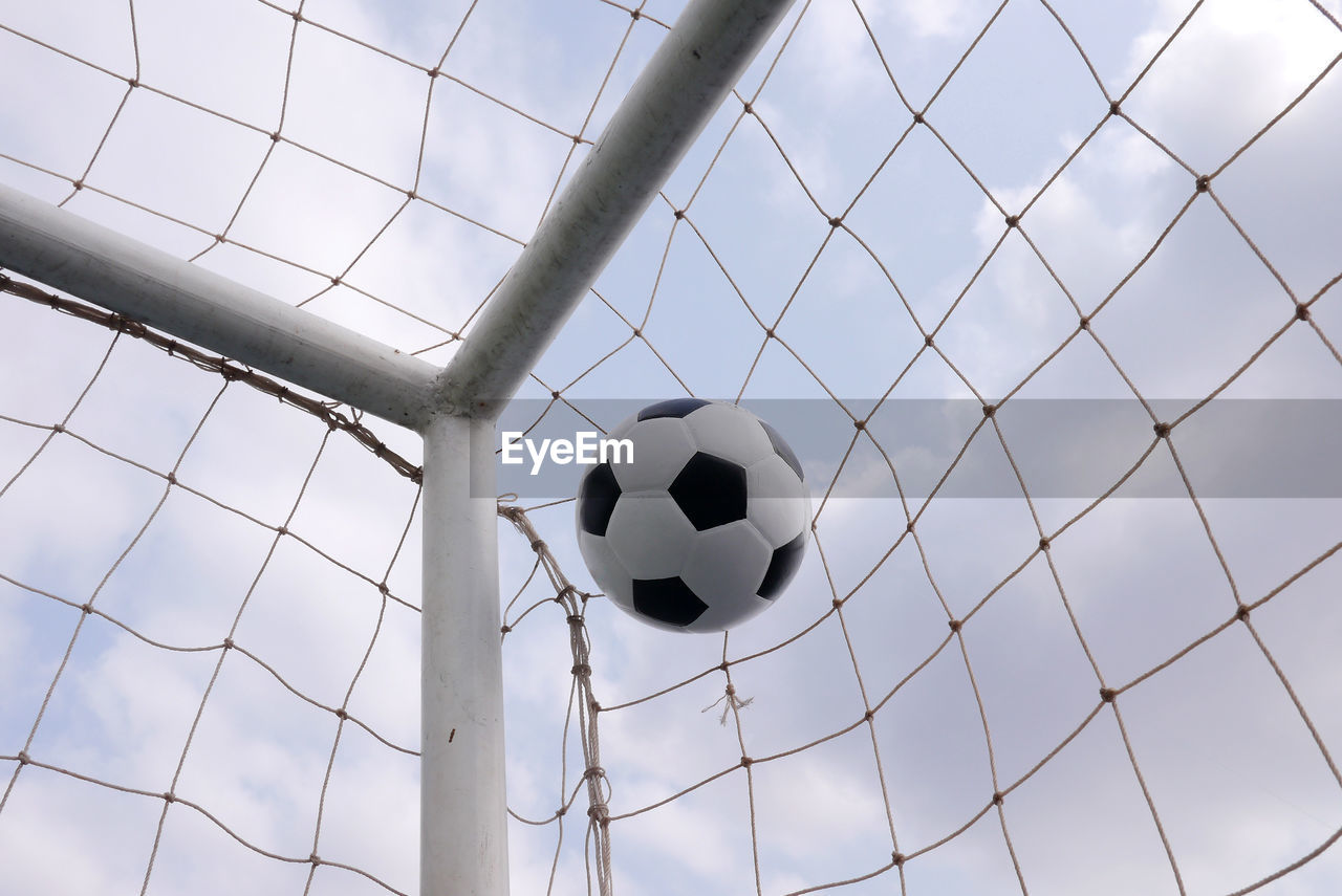 Low angle view of soccer ball on grass against sky