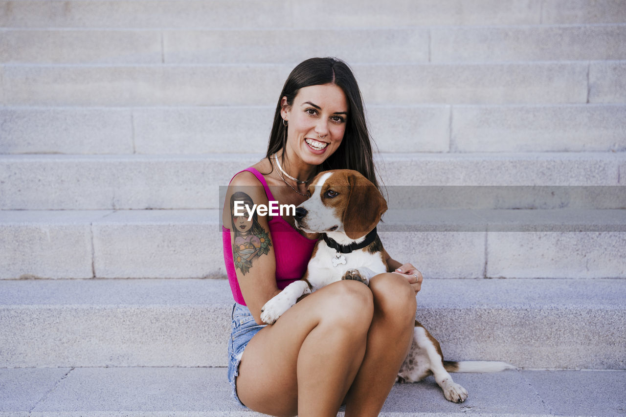 Portrait of woman with dog sitting on staircase