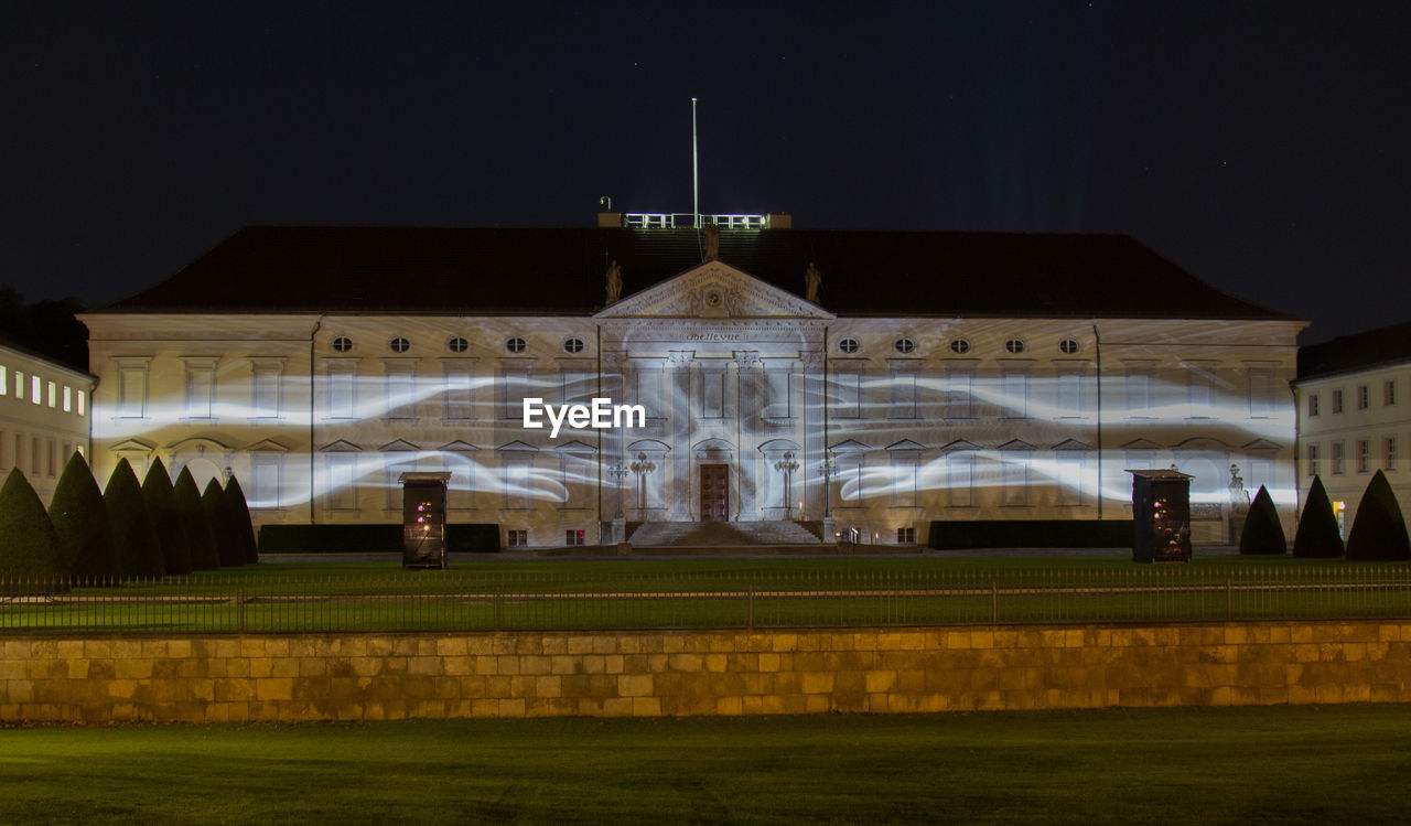 ILLUMINATED BUILT STRUCTURE AGAINST SKY AT NIGHT