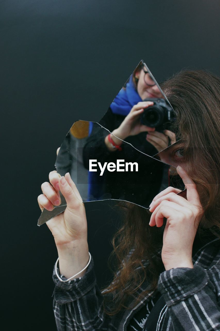 side view of woman using mobile phone against black background