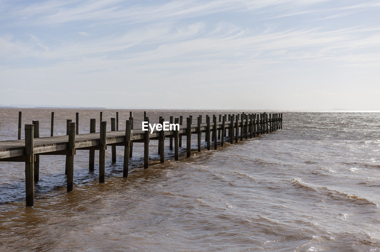 Pier over sea against sky, in the itapuã park, guaiba river, and the skyline in the background