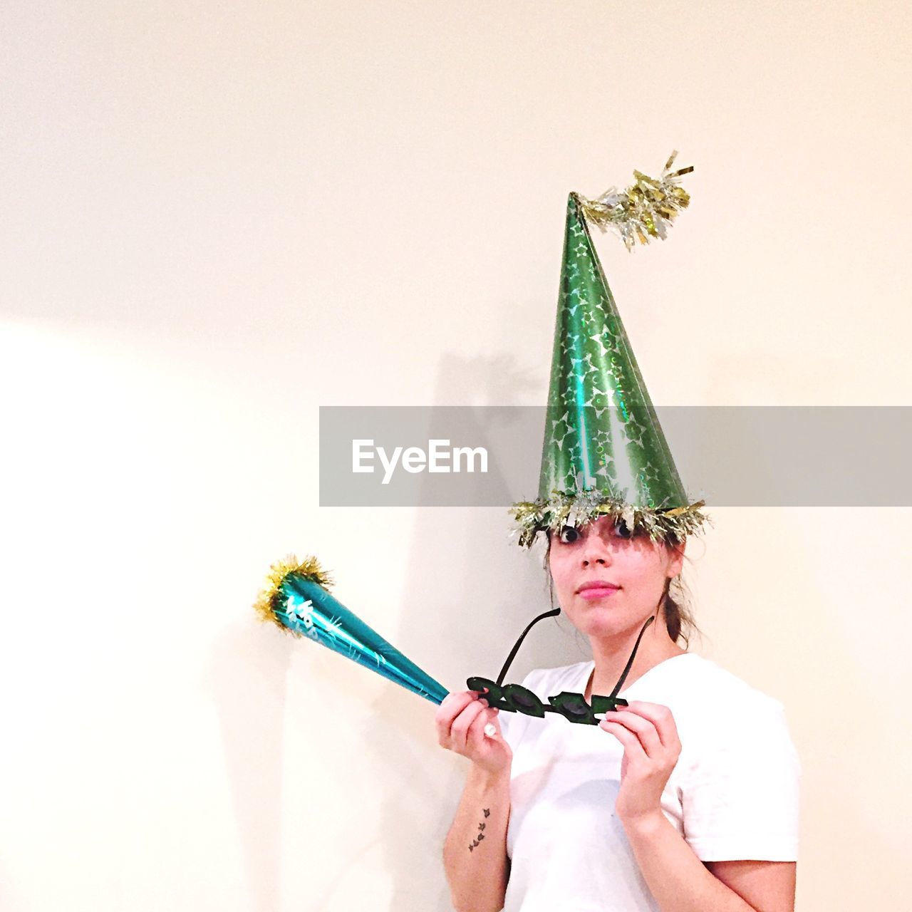 Portrait of young woman wearing party hat over white background