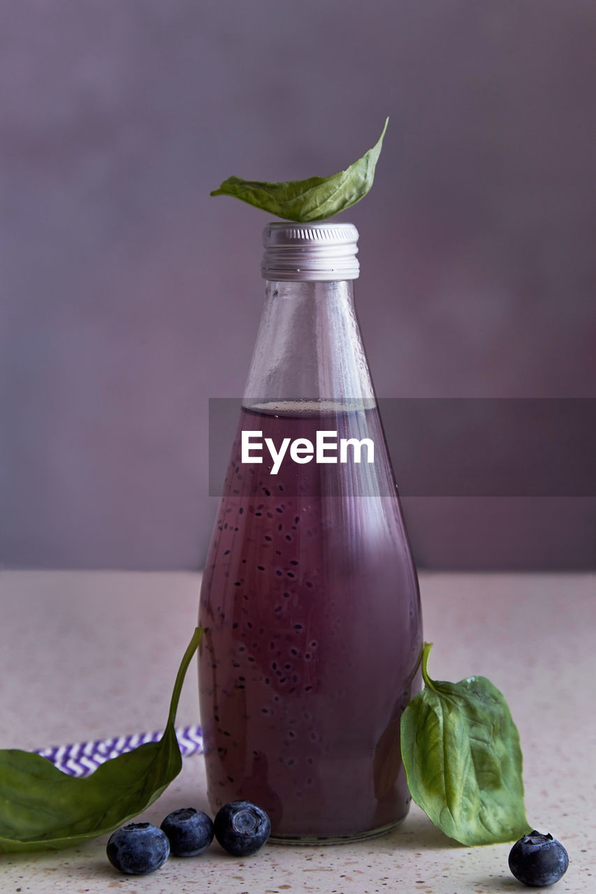 Non-alcoholic healthy organic bottle of drink with blueberries, seeds, basil extract, leaves. 