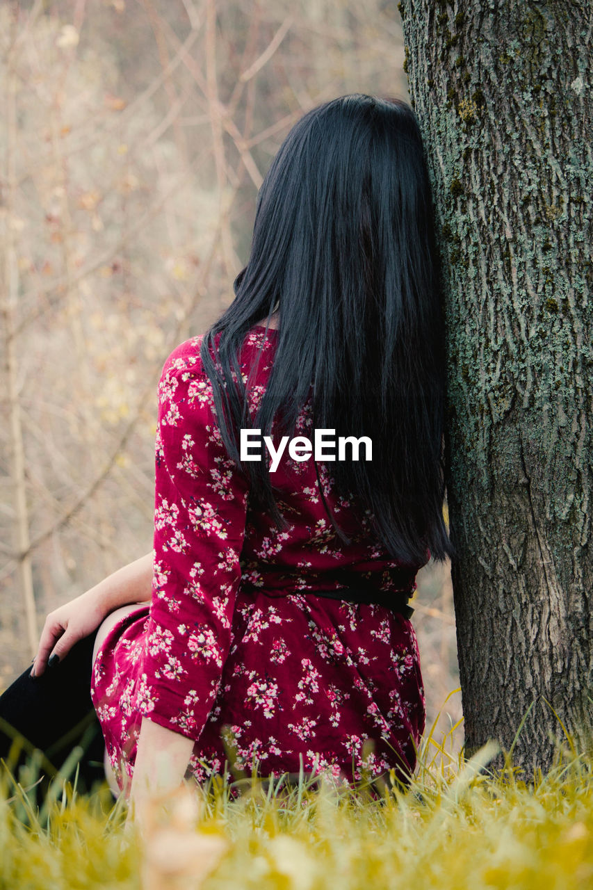 Rear view of woman sitting on field