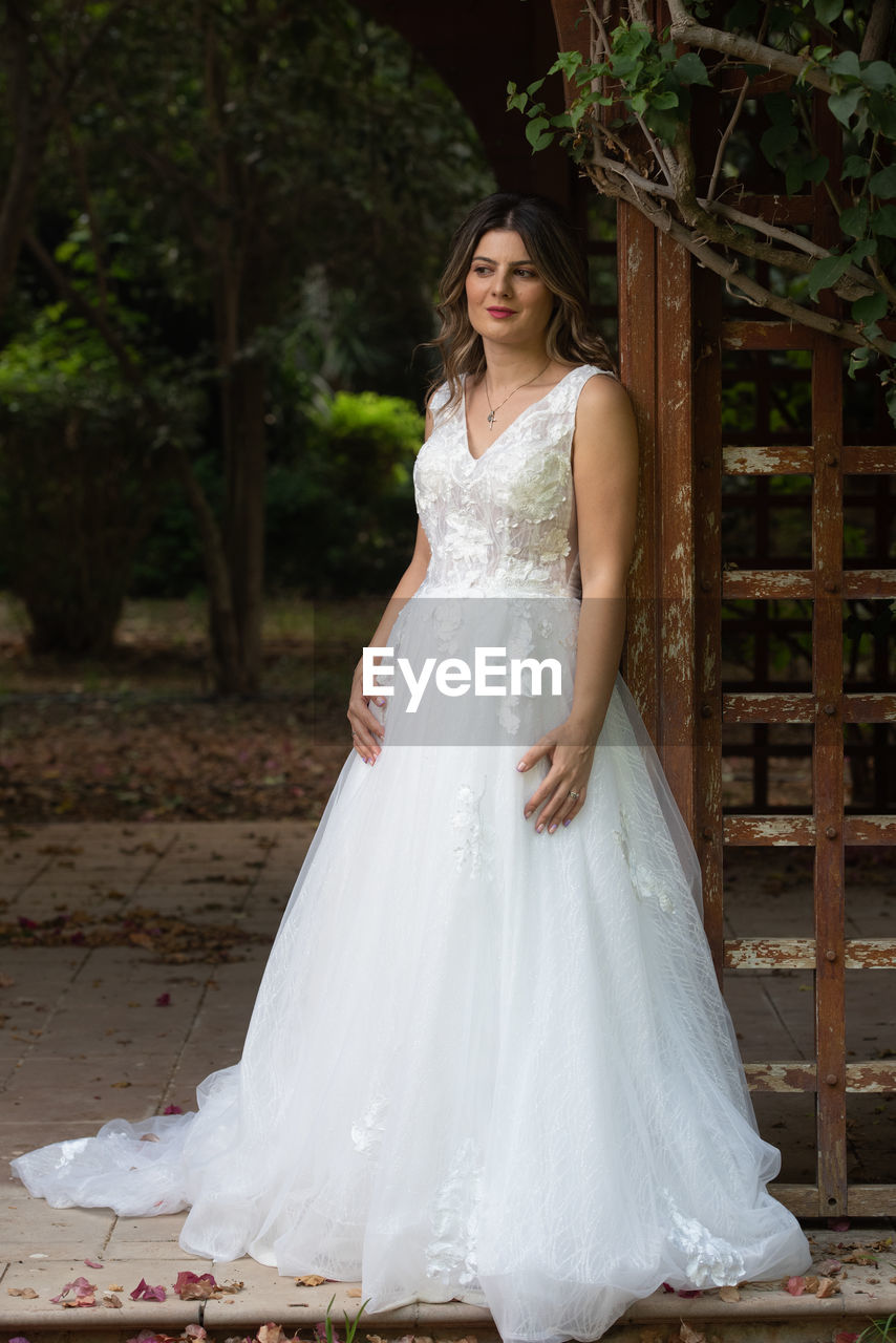 Pregnant happy smiling bride with white wedding dress posing outdoor