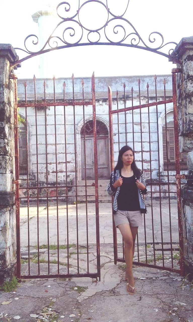 Young woman entering into gate against building