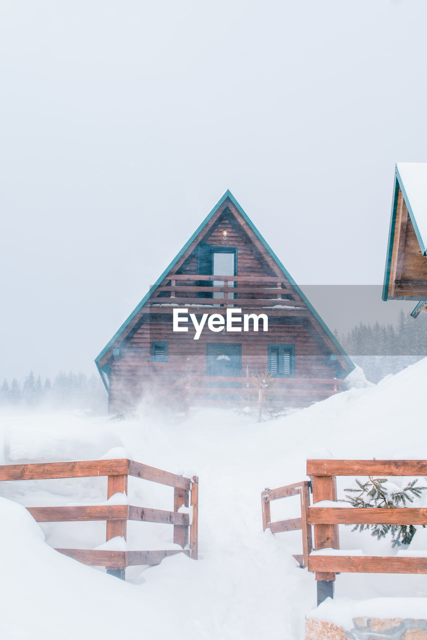 BUILDING COVERED WITH SNOW AGAINST SKY