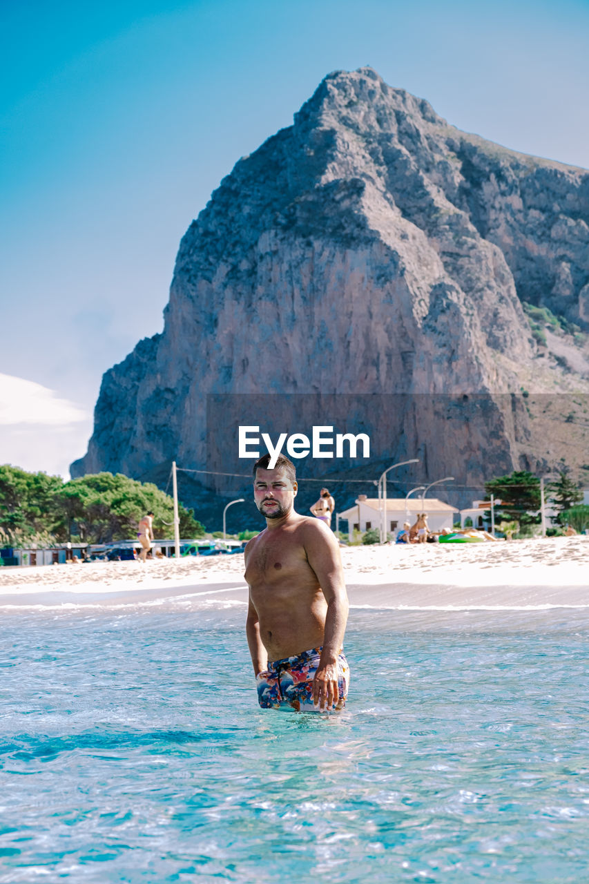 MAN IN SWIMMING POOL AGAINST SEA