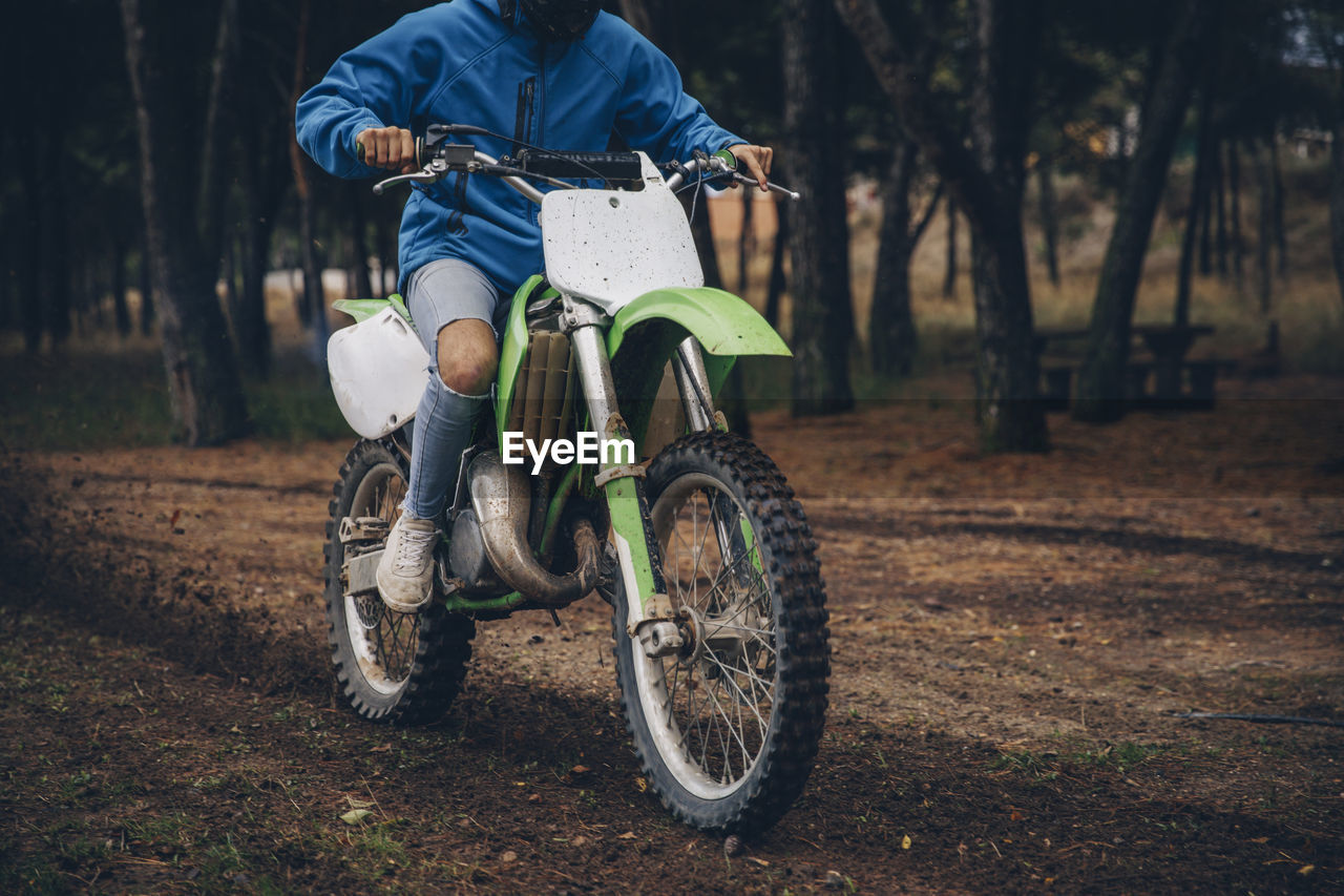 Teenage male rider riding on dirt track at forest during autumn