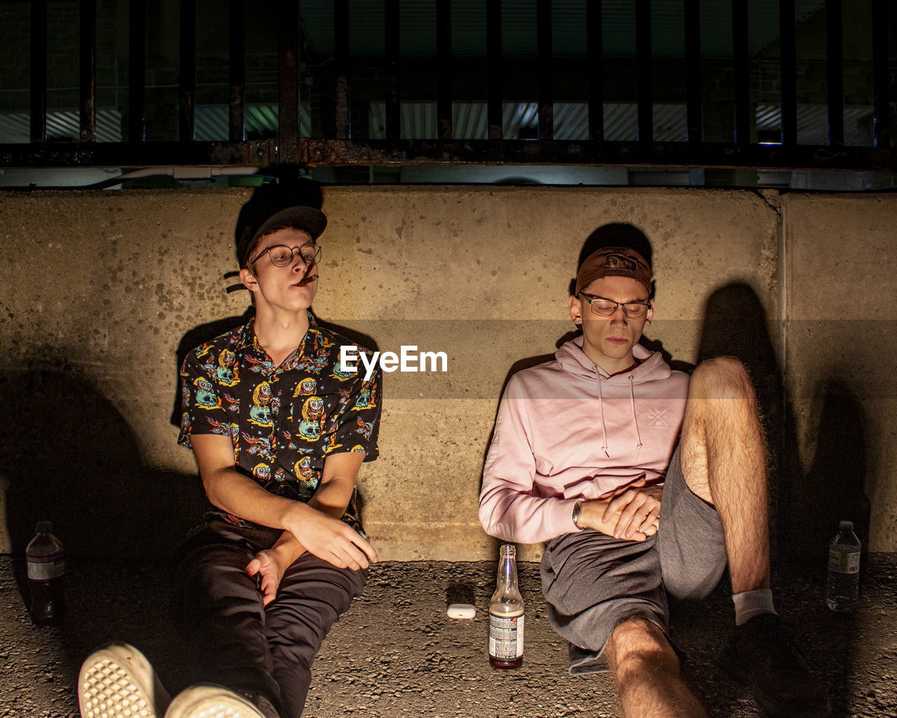 Full length view of young men drinking sitting outdoors