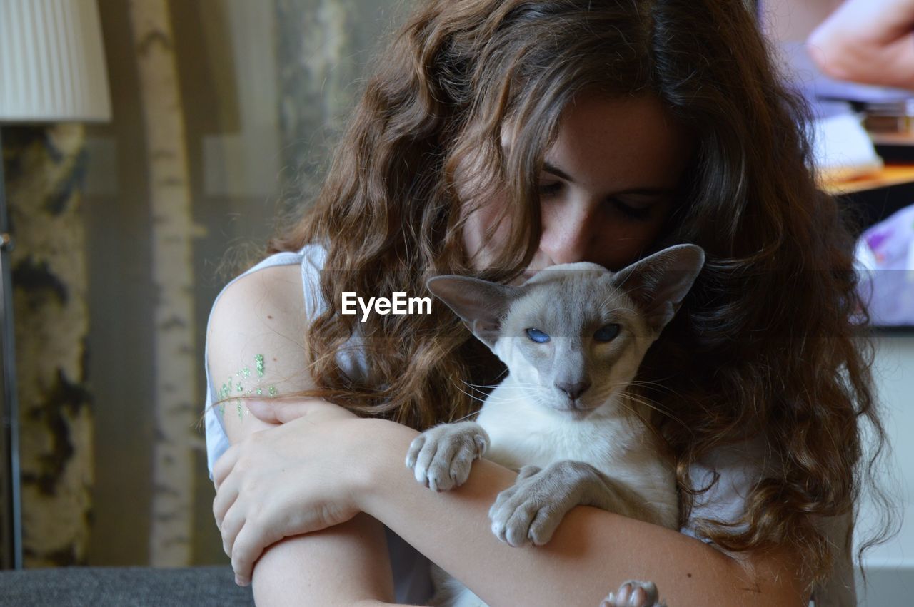Close-up of young woman hugging cat