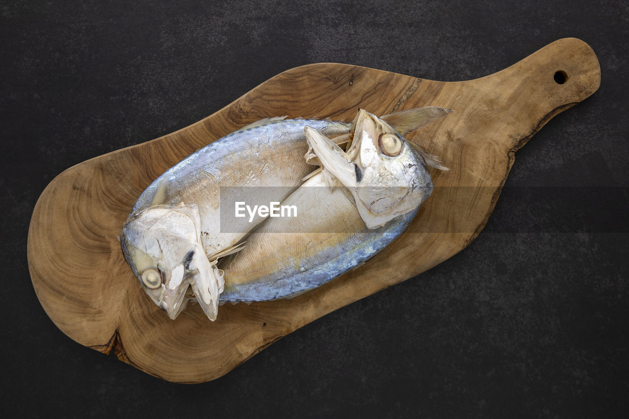 HIGH ANGLE VIEW OF FISH ON TABLE AGAINST BLACK BACKGROUND