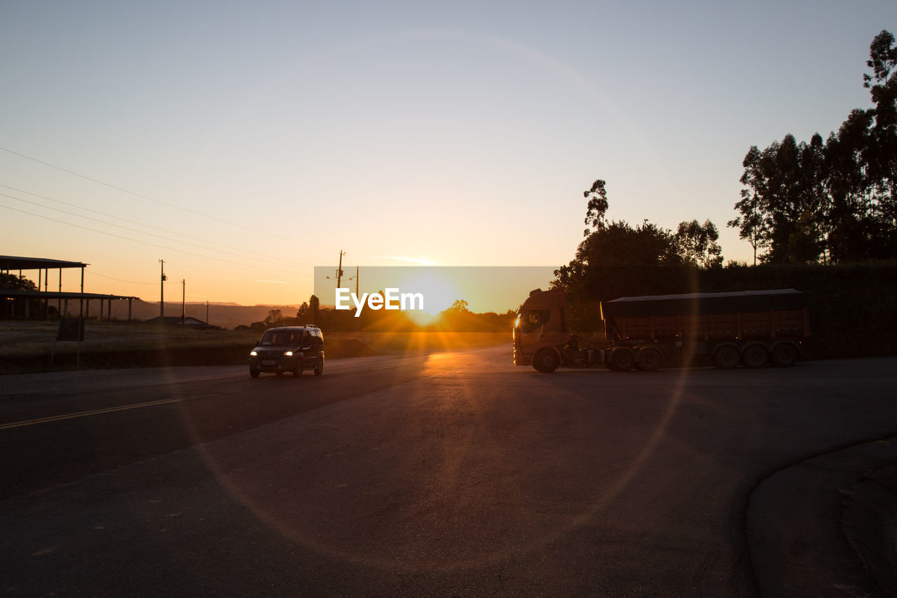 Vehicles on road at sunset