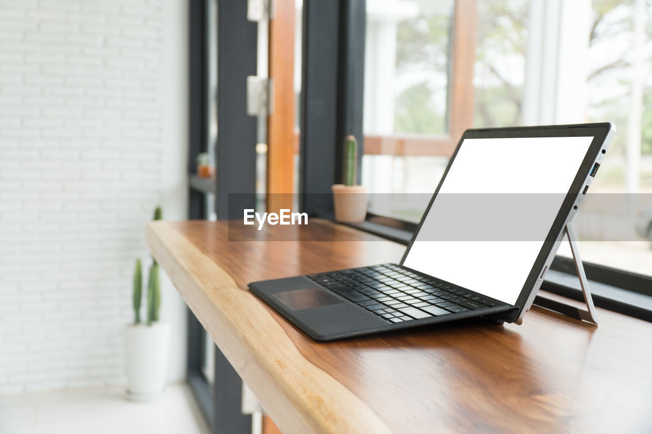 Close-up of laptop on table by window