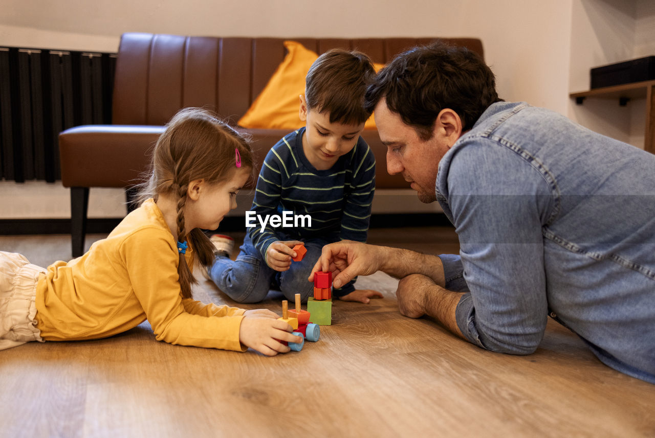 side view of mother playing with toy blocks at home