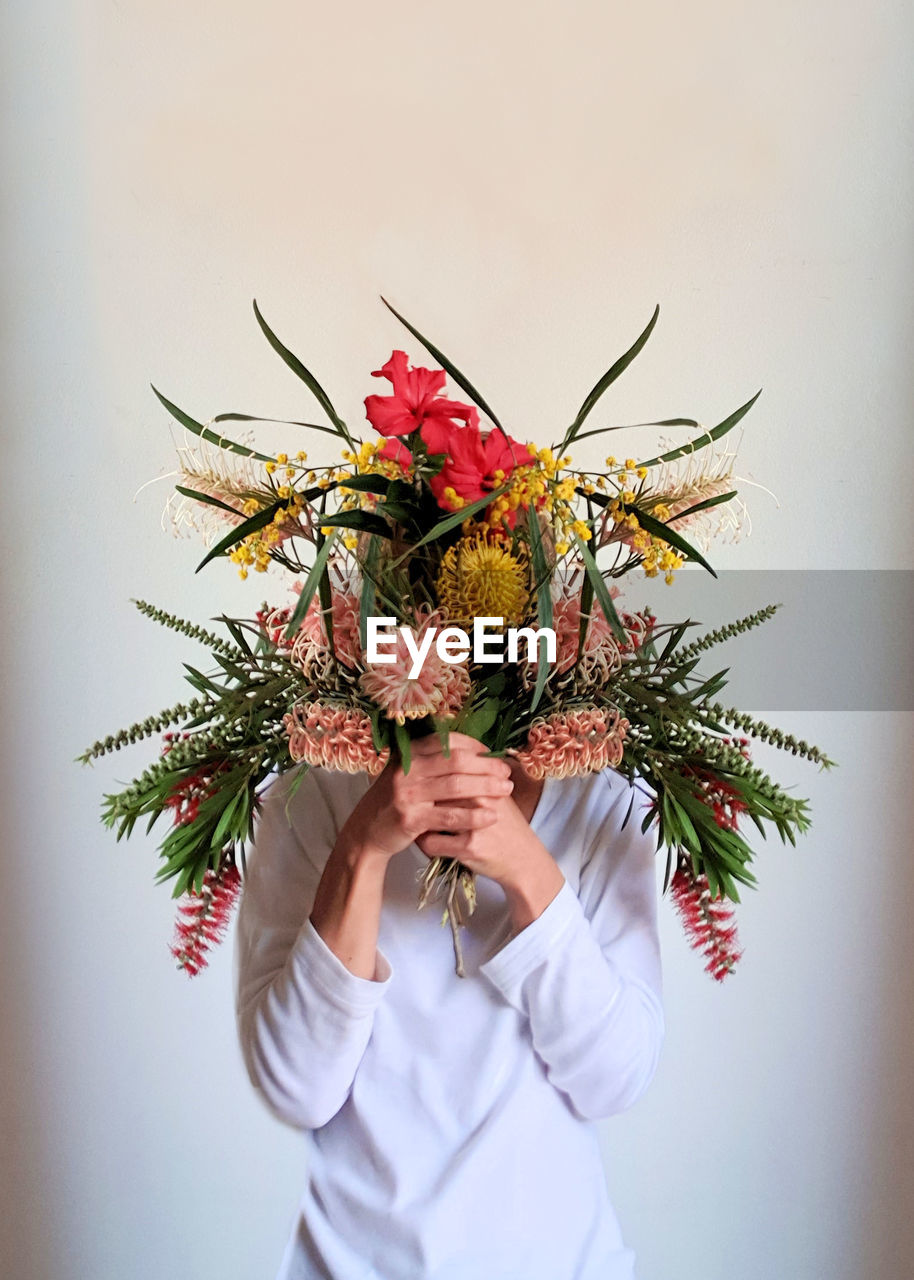 Woman holding bouquet flowers against white background 