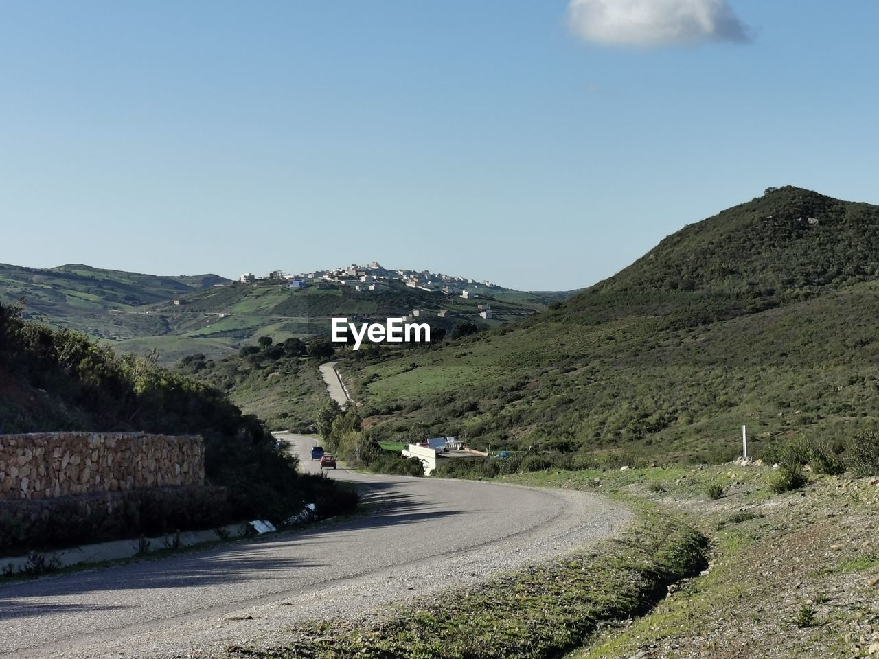 Road leading towards mountains against clear sky